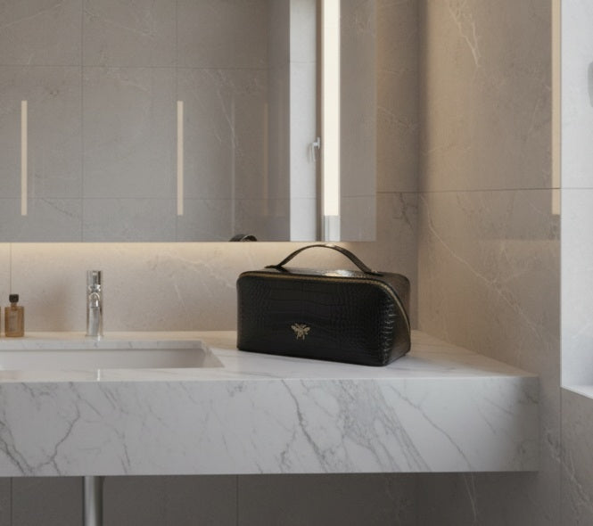 Black toiletry bag on a marble countertop in a modern bathroom.